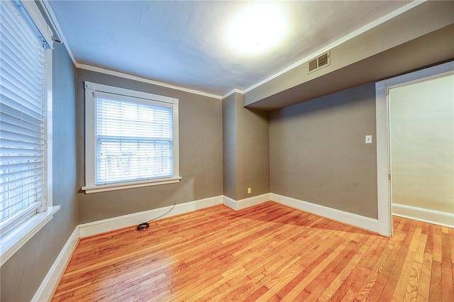 empty room featuring light wood-type flooring and crown molding