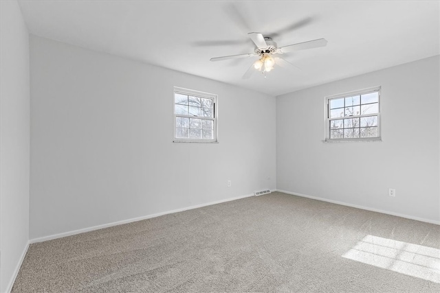 carpeted spare room featuring ceiling fan and a wealth of natural light