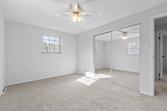 unfurnished bedroom with ceiling fan, light carpet, and a closet