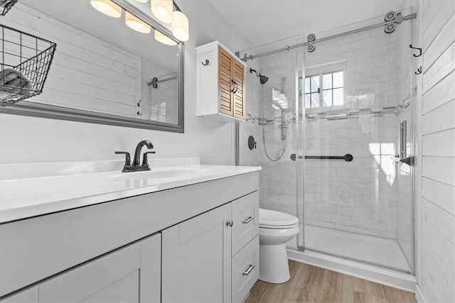 bathroom with wood-type flooring, vanity, toilet, and a shower with shower door