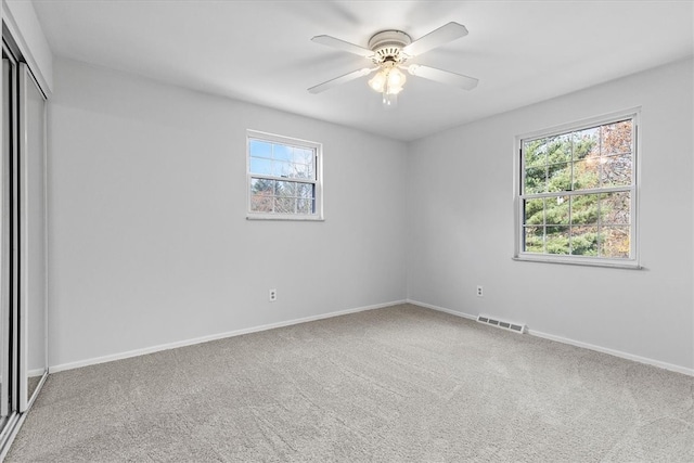 unfurnished bedroom with multiple windows, ceiling fan, a closet, and carpet floors