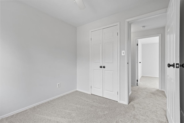 unfurnished bedroom with ceiling fan, light colored carpet, and a closet