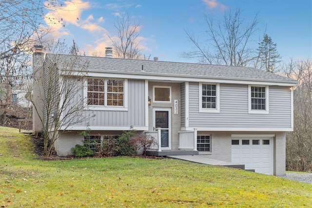 raised ranch featuring a garage and a lawn