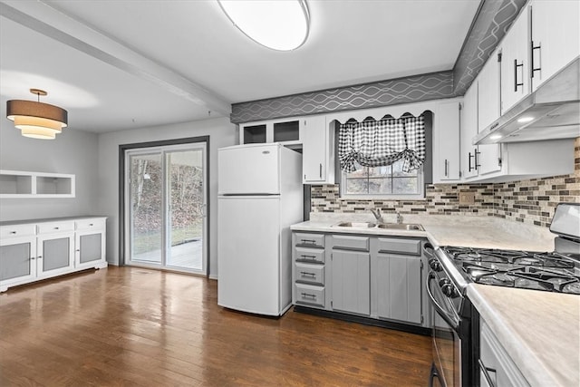 kitchen with white refrigerator, sink, stainless steel gas stove, dark hardwood / wood-style floors, and white cabinetry