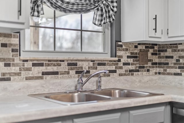 kitchen featuring white cabinets, sink, and tasteful backsplash