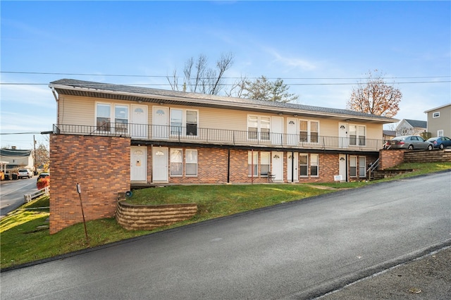 townhome / multi-family property with a balcony and a front lawn