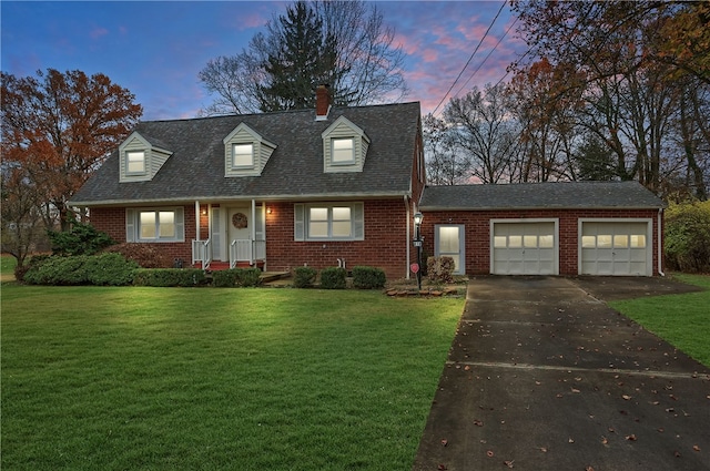 cape cod house featuring a garage and a yard