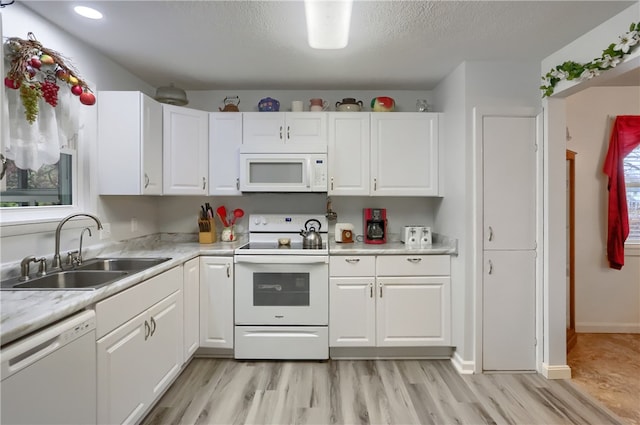 kitchen with white cabinetry, sink, light hardwood / wood-style floors, and white appliances