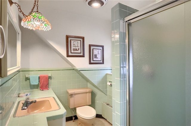 bathroom with radiator, walk in shower, toilet, vanity, and tile walls