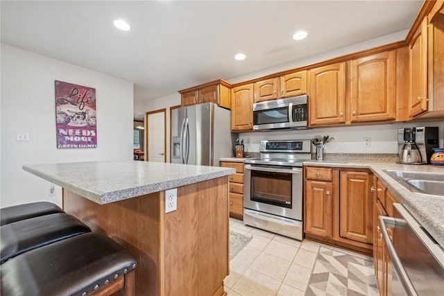 kitchen featuring appliances with stainless steel finishes, light tile patterned floors, a kitchen breakfast bar, and sink