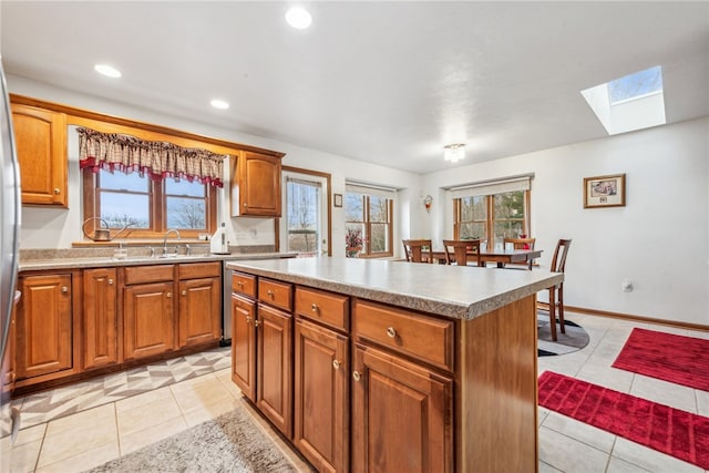 kitchen with a center island, light tile patterned floors, sink, and a skylight