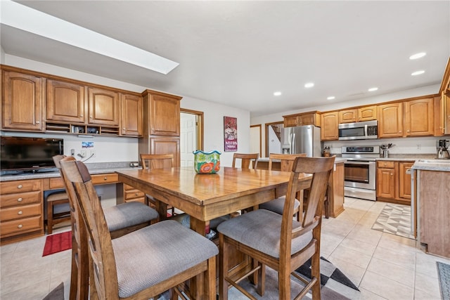 dining space featuring light tile patterned floors and a skylight