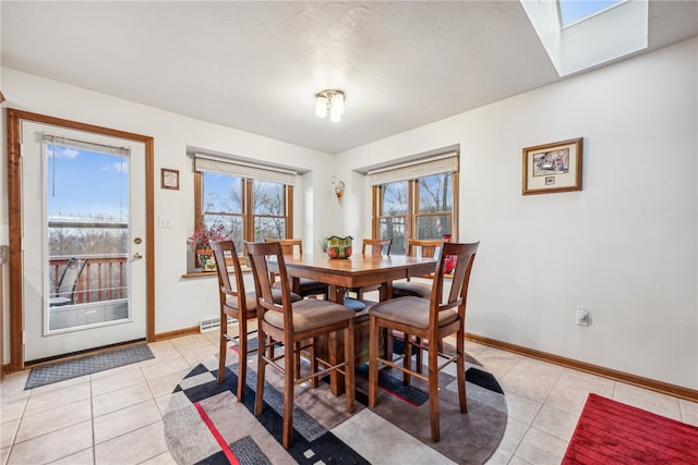 dining area with a skylight and light tile patterned floors