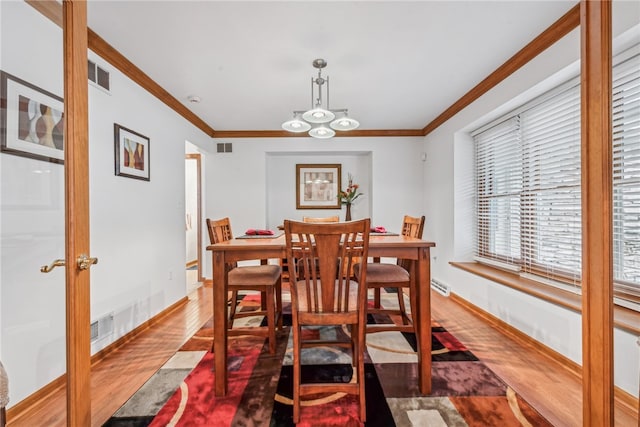 dining area with hardwood / wood-style flooring, a notable chandelier, and ornamental molding