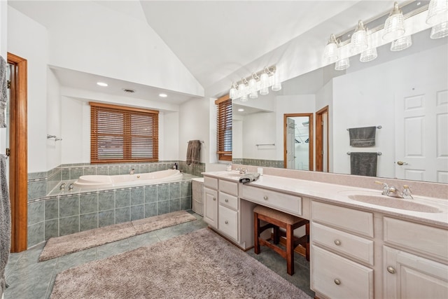 bathroom featuring tile patterned floors, vanity, a relaxing tiled tub, and vaulted ceiling