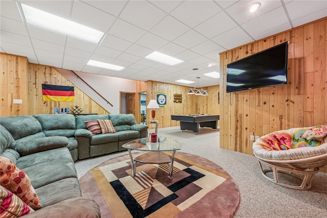 carpeted living room with a paneled ceiling, wooden walls, and billiards