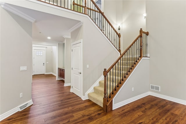 stairs featuring wood-type flooring and ornamental molding