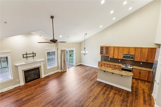 kitchen featuring dark hardwood / wood-style flooring, light stone counters, appliances with stainless steel finishes, and tasteful backsplash