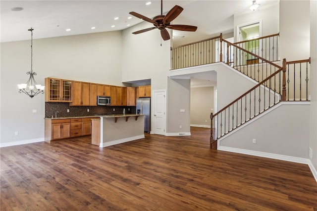 kitchen with a center island, stainless steel appliances, dark hardwood / wood-style flooring, a towering ceiling, and a kitchen bar