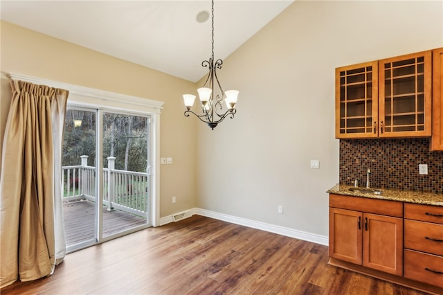 unfurnished dining area featuring a notable chandelier, dark hardwood / wood-style flooring, sink, and vaulted ceiling