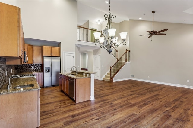 kitchen with pendant lighting, high vaulted ceiling, an island with sink, dark hardwood / wood-style flooring, and stainless steel appliances