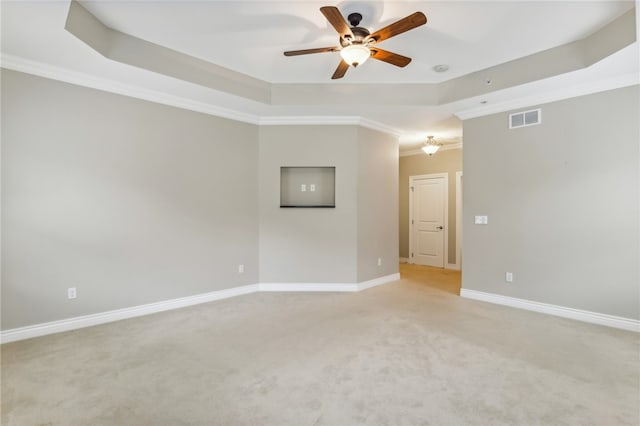 empty room with a tray ceiling, ceiling fan, and ornamental molding