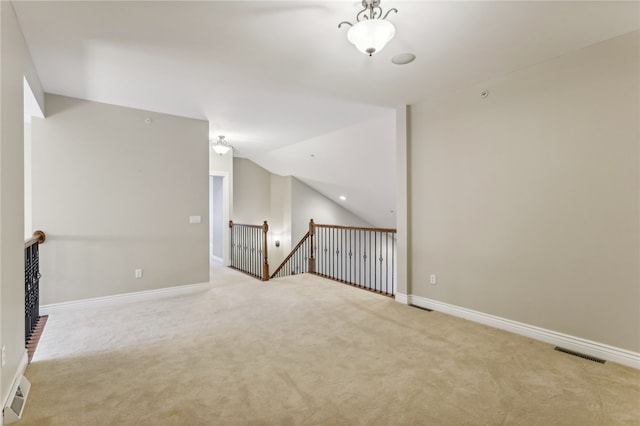 carpeted spare room with vaulted ceiling