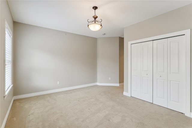 unfurnished bedroom featuring light carpet and a closet