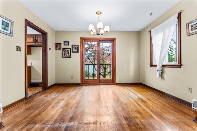 spare room featuring wood-type flooring and an inviting chandelier