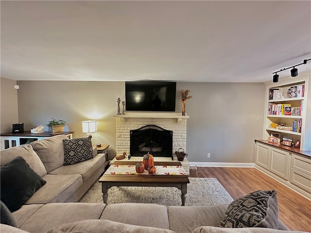 living room featuring a fireplace, rail lighting, and light hardwood / wood-style floors