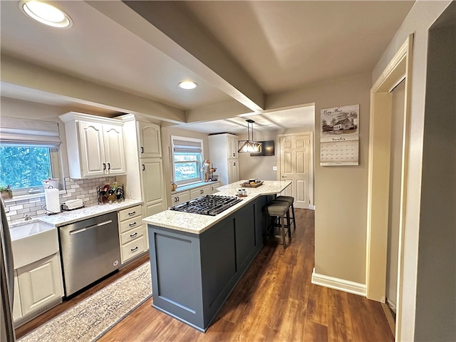 kitchen featuring a center island, dark wood-type flooring, decorative light fixtures, white cabinets, and appliances with stainless steel finishes