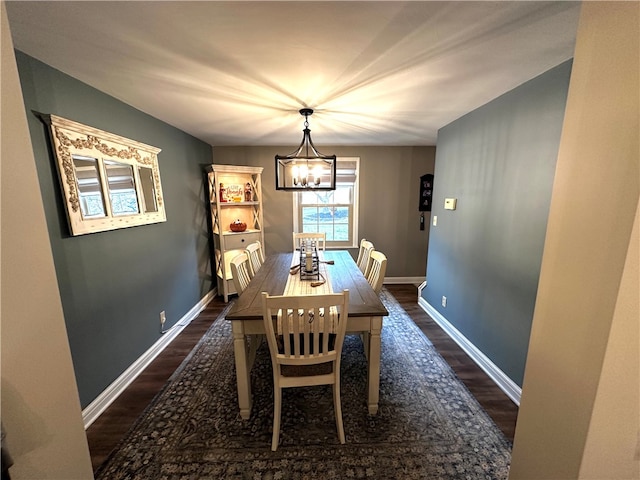 dining area with dark hardwood / wood-style floors and an inviting chandelier