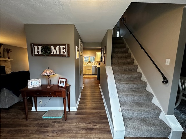 stairs featuring a stone fireplace and wood-type flooring