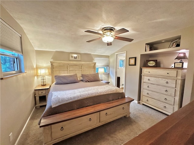 carpeted bedroom with ceiling fan, lofted ceiling, and a textured ceiling