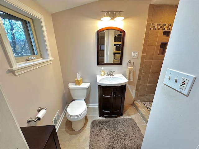 bathroom with tile patterned floors, vanity, toilet, and tiled shower