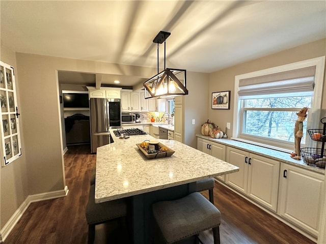 kitchen with pendant lighting, white cabinets, a kitchen island, a kitchen bar, and stainless steel appliances