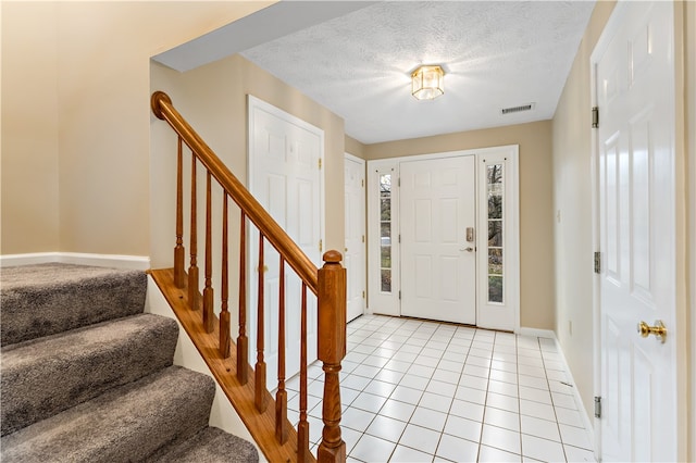 entryway with light tile patterned floors and a textured ceiling