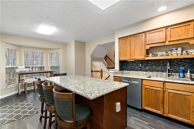 kitchen featuring light stone countertops, dark hardwood / wood-style flooring, sink, dishwasher, and a kitchen island