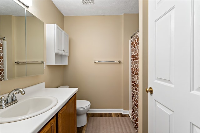 bathroom with vanity, toilet, wood-type flooring, and a textured ceiling