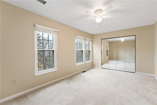 unfurnished bedroom with ceiling fan, light colored carpet, and a closet