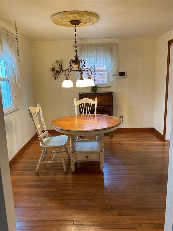 dining space with dark wood-type flooring, a wealth of natural light, and an inviting chandelier