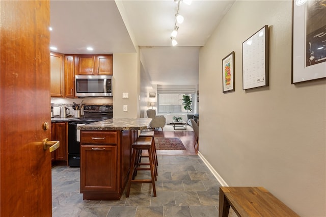 kitchen featuring a kitchen breakfast bar, black range with electric stovetop, a center island, and tasteful backsplash