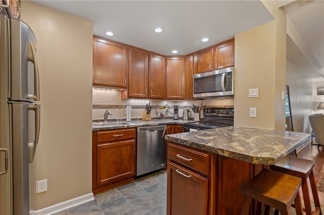 kitchen with decorative backsplash, dark stone counters, stainless steel appliances, sink, and a breakfast bar area