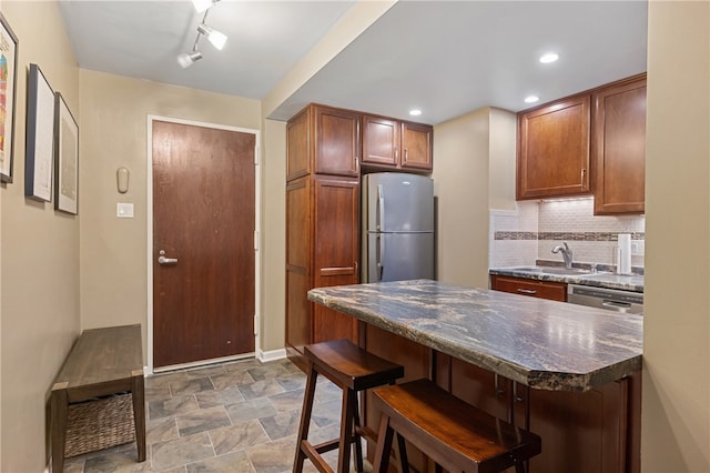 kitchen featuring backsplash, sink, a breakfast bar area, and stainless steel appliances