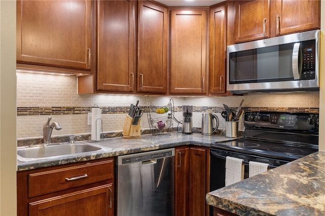 kitchen with backsplash, sink, stainless steel appliances, and dark stone counters