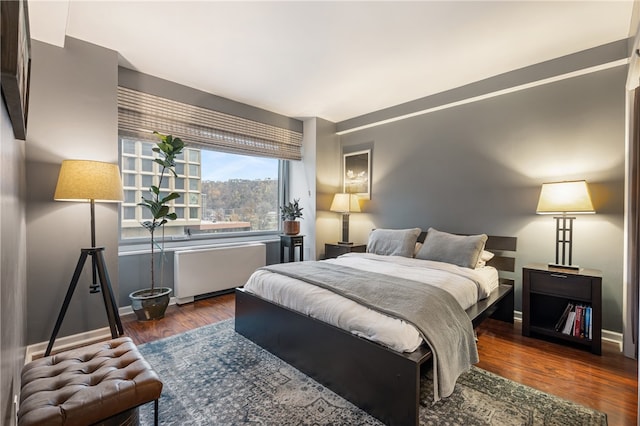 bedroom with radiator heating unit and dark hardwood / wood-style floors