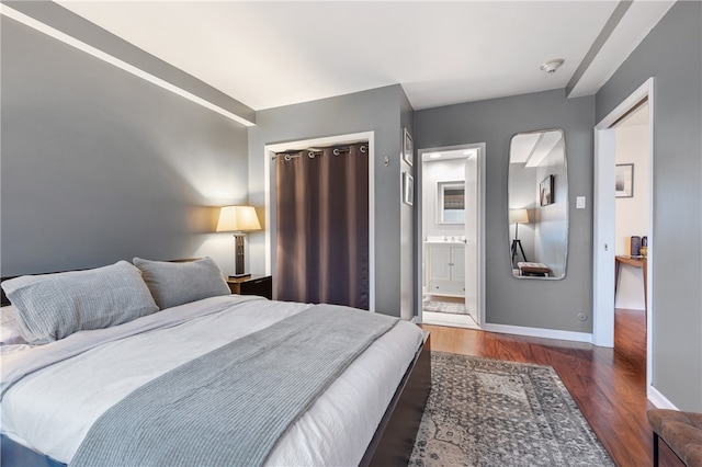 bedroom with connected bathroom and dark hardwood / wood-style floors