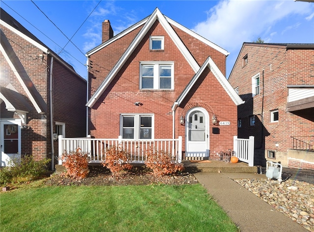 tudor house featuring a porch and a front yard