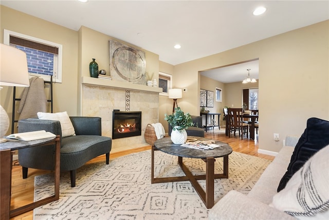 living room featuring a notable chandelier, light hardwood / wood-style flooring, and a tiled fireplace