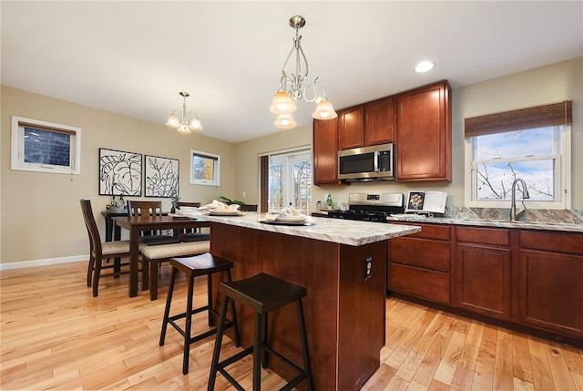 kitchen with a center island, stainless steel appliances, an inviting chandelier, and light hardwood / wood-style floors